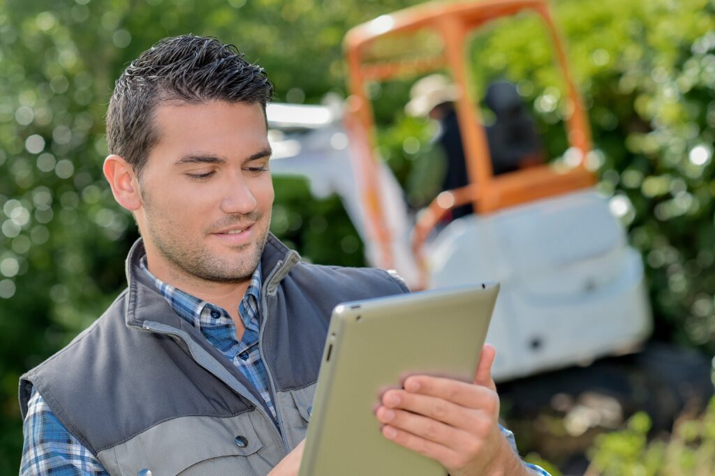 Landscape worker looking at tablet with equipment in the background