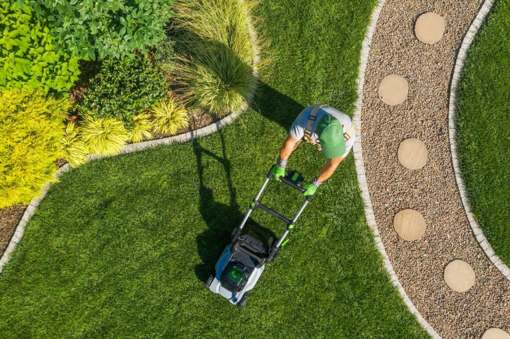 Landscaper mowing lawn from above