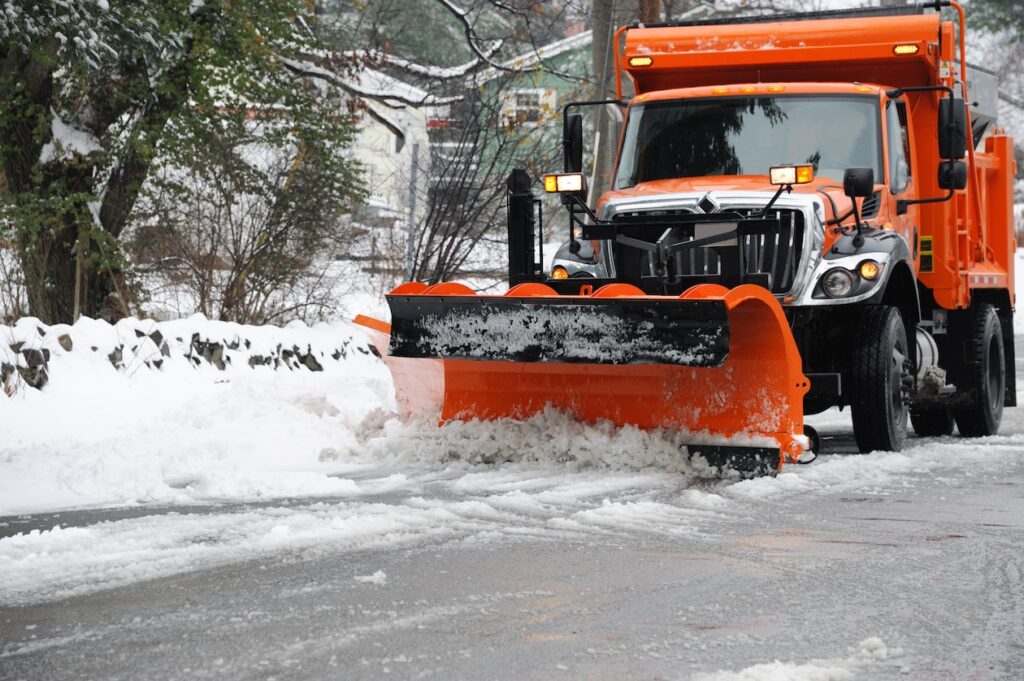 Snowplow clearing a residential street after a blizzard, ensuring safe winter road conditions.