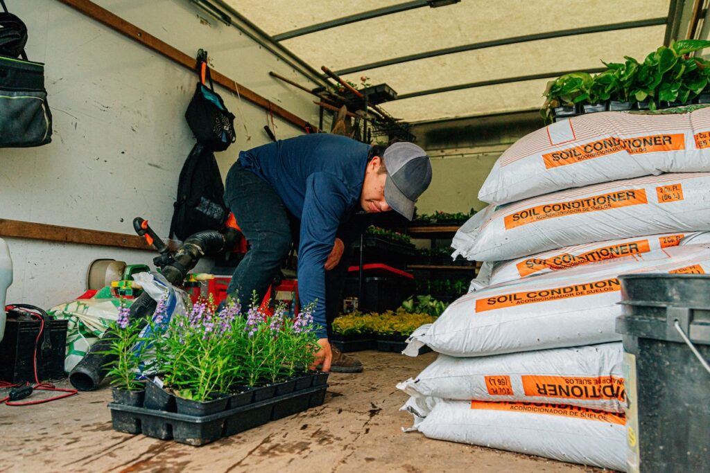 Lawn care worker loading flowers in back of box truck