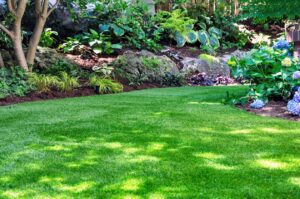 Landscaped backyard with artificial turf lawn, stone pathway, outdoor seating area, and wooded garden design in a small residential space.