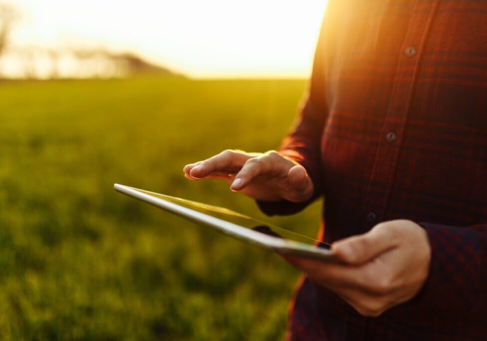 Lawn care worker using a tablet to track scheduling and service progress in the field.