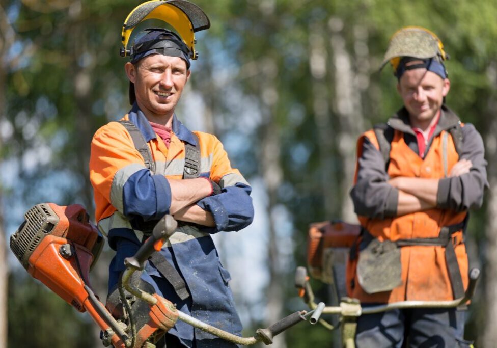 Two lawncare workers in orange vests