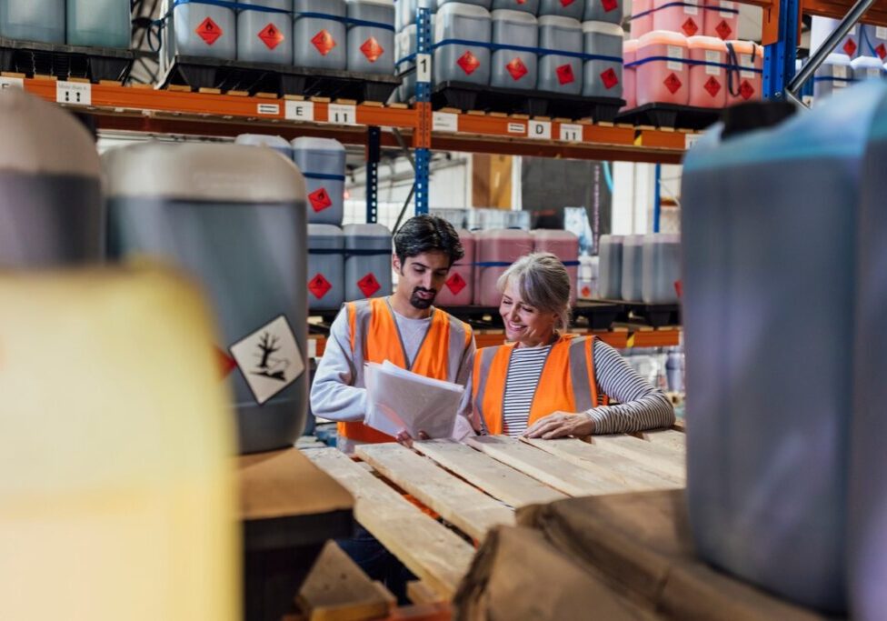 Workers in chemical warehouse looking at paperwork.